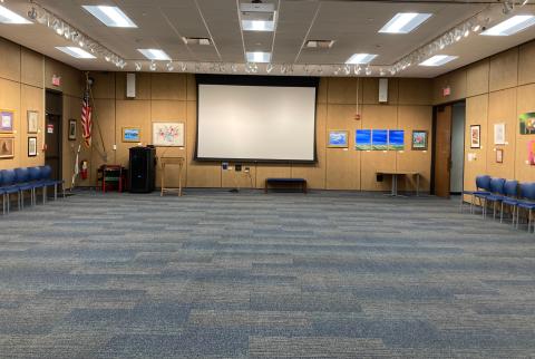 Large open room with carpet and a projection screen in the front