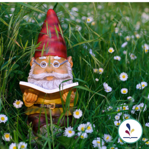 Gnome figurine reading a book in grass with small flowers