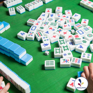 Two people playing Mahjong; tiles on table