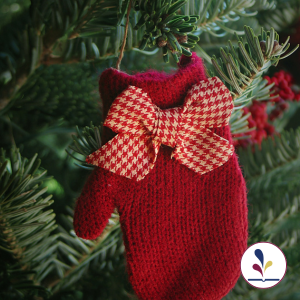 A red mitten hanging on an evergreen branch